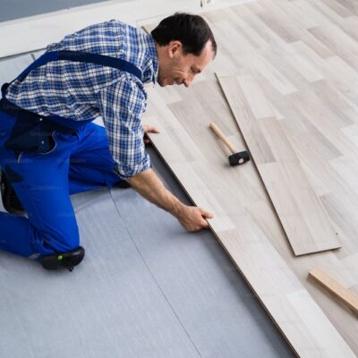 Worker Installing Home Floor. Carpenter Laying Laminate Flooring